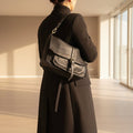 Borsa cartella Pito’s|Bag Ale in vera pelle nera con tracolla, indossata a spalla su cappotto nero