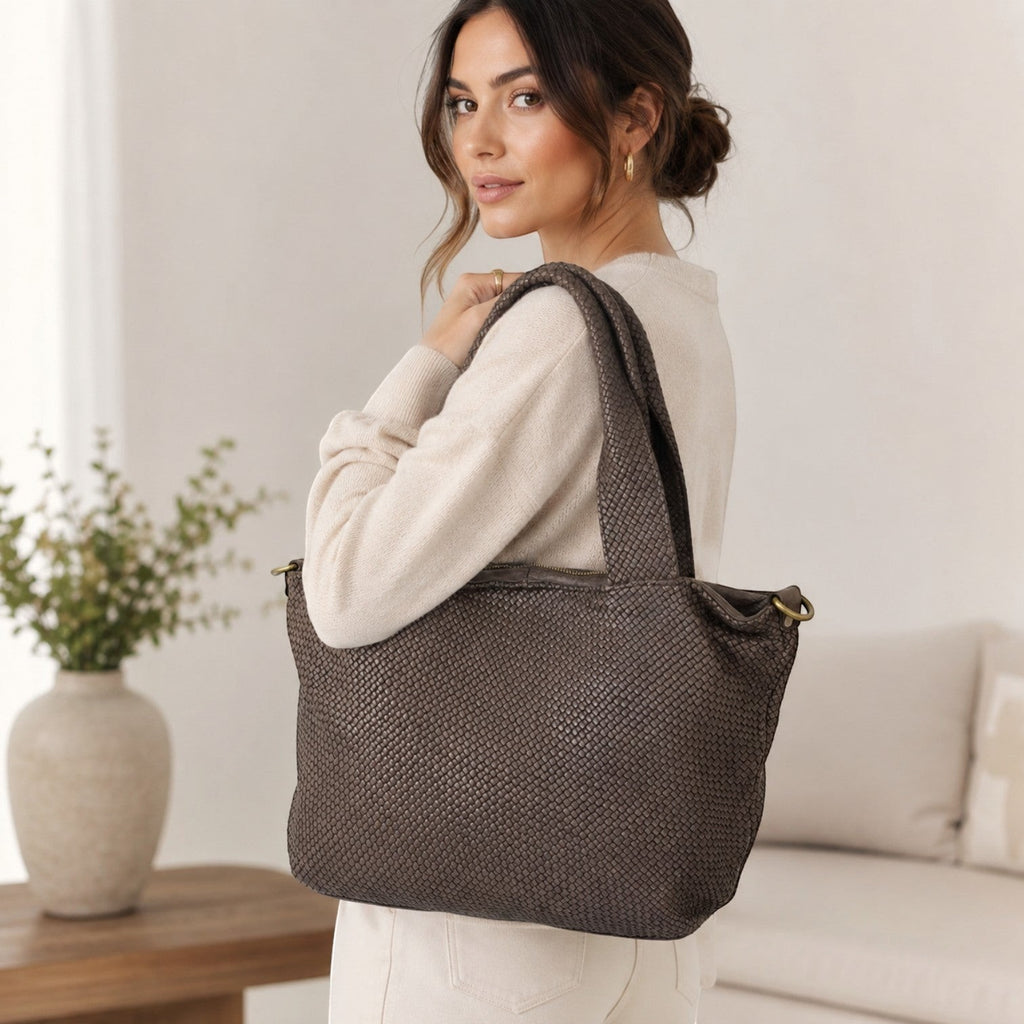 Modella indossa borsa Pito’s|Bag media in pelle marrone con lavorazione intrecciata e dettagli color ottone.