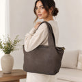 Modella indossa borsa Pito’s|Bag media in pelle marrone con lavorazione intrecciata e dettagli color ottone.