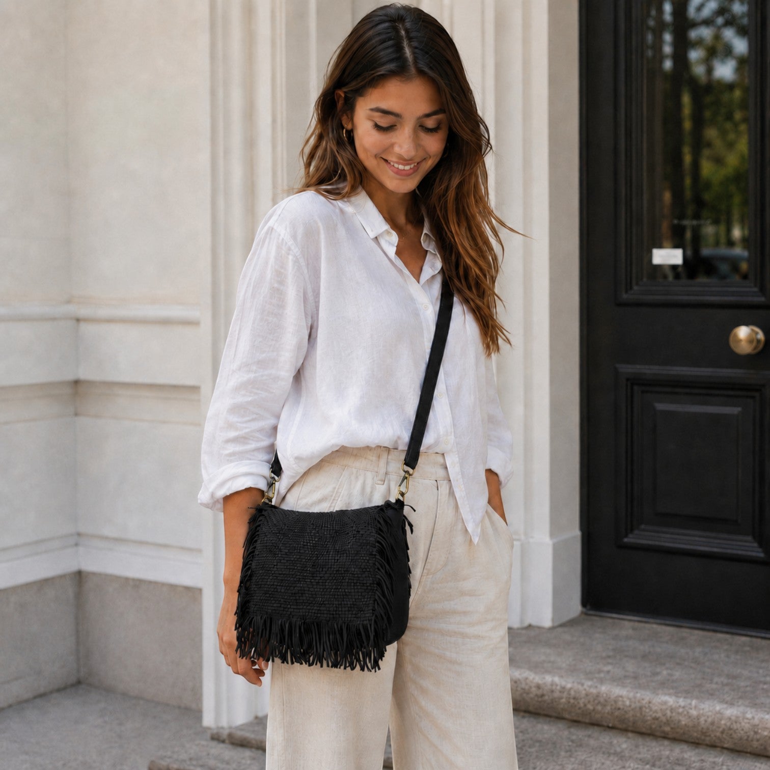 Modella indossa la borsa a tracolla nera Pito’s|Bag Fru Fru in pelle intrecciata con frange e dettagli in ottone