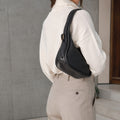 Borsetta Pito’s|Bag nera in pelle intrecciata con manico a spalla, indossata su un maglione bianco.
