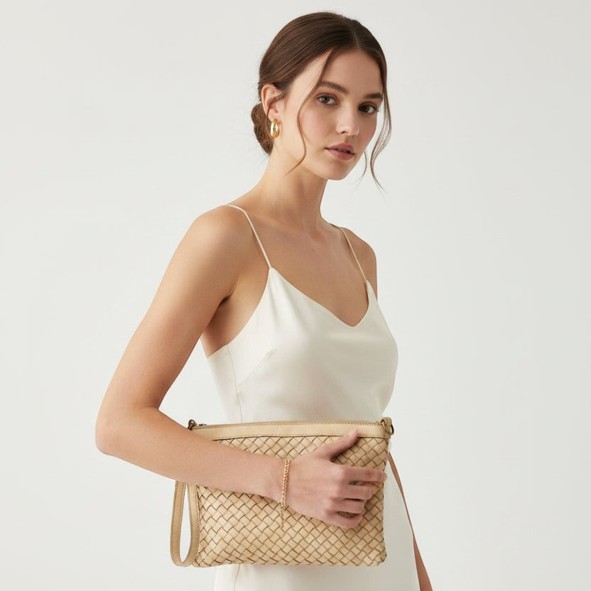 Modella indossa la pochette Pito’s|Bag Giovy in pelle color cuoio con lavorazione a intreccio e laccio da polso.